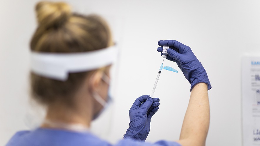 Sjuksköterska i blåa kläder förbereder en covid-19-vaccindos