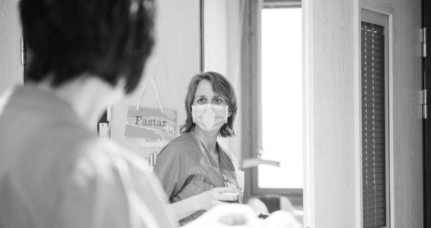 två sjuksköterskor tittar på varandra, en har munskydd