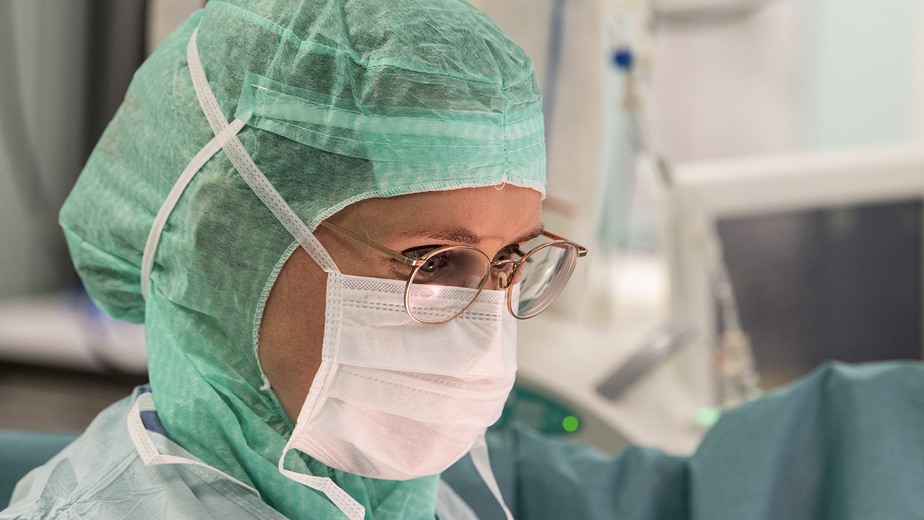 Bild som visar en läkare i operationssal redo för operation. Iförd munskydd, huvudskydd och glasögon.