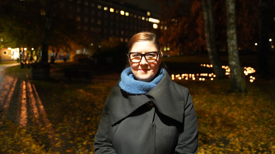 Linda Gyllström Krekula har svarta glasögon, blå stickad halsduk och en svart kappa med stort slag.