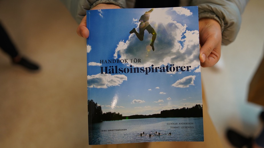 Handbok för hälsoinspiratörer med ett fotoomslag som visar en varm sommardag och människor som badar