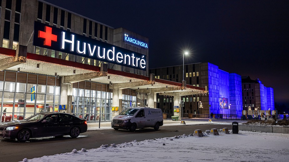 Karolinskas fasad i Huddinge, upplyst i blått.