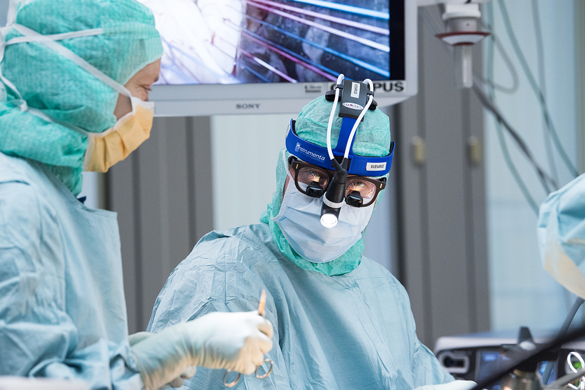Två kirurger under operation varav den ena tittar in i kameran