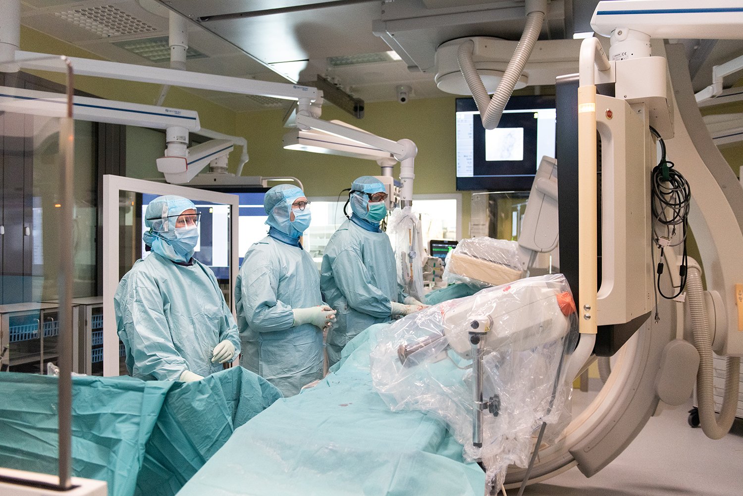 Tre operationsklädda kärlkirurger i operationssal