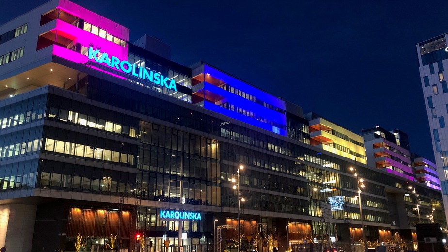Fasaden på Karolinska i Solna, upplyst i olika färger.
