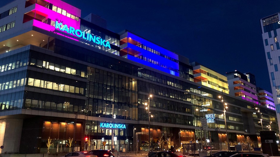 Fasaden på Karolinska i Solna, upplyst i olika färger.