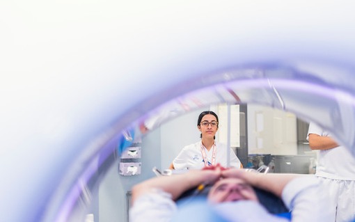 Bild på patient inuti röntgenutrustning. En röntgensjuksköterska tittar in.