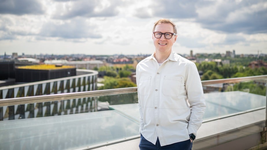 Petter Brodin står på ett hustak med utsikt över Karolinska Institutets ovala byggnad.