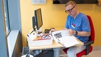 Petter Brodin sitter vid sitt skrivbord i blåvita arbetskläder.