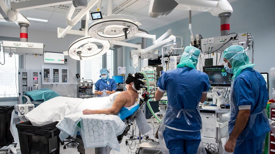 Bild från operationssal där läkarteam är redo, precis som anonym patient. Högteknologisk utrustning.