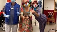 Eva Riepe som clownen Gajans och kollegan Ylva Magnusson som clownen Margott står med en medarbetare på vaccinationsmottagningen i Karolinska, Huddinge.