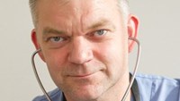 Peter Bergman har kort gråsprängt hår och blå läkarkläder på sig.