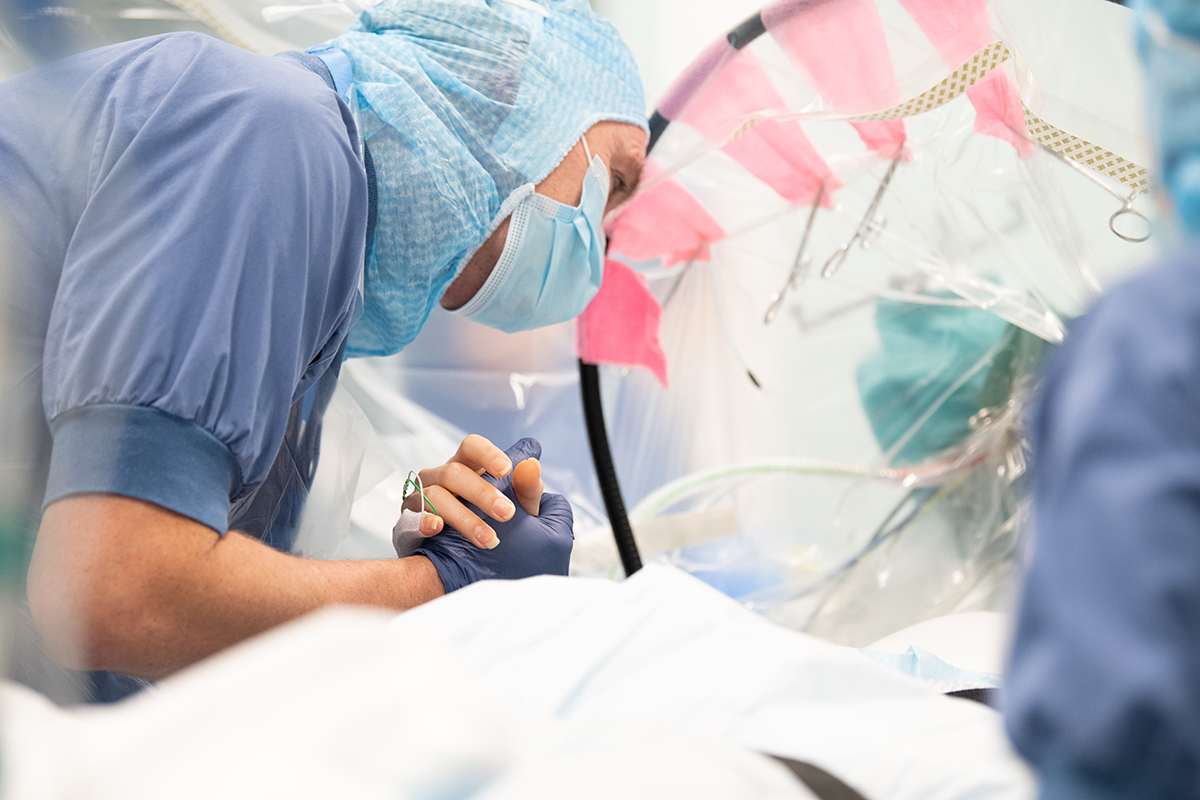Neurokirurg håller handen och pratar med patient under pågående hjärnoperation