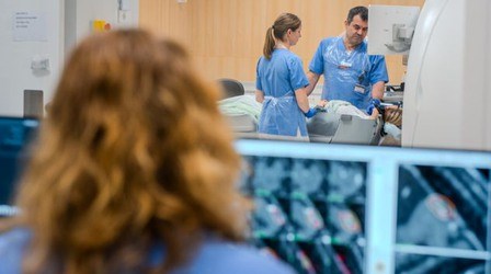 Vårdpersonal vid bildskärmar övervakar förberedelser för undersökning
