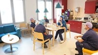 Cechael fikar med kollegor i den gemensamma matsalen.