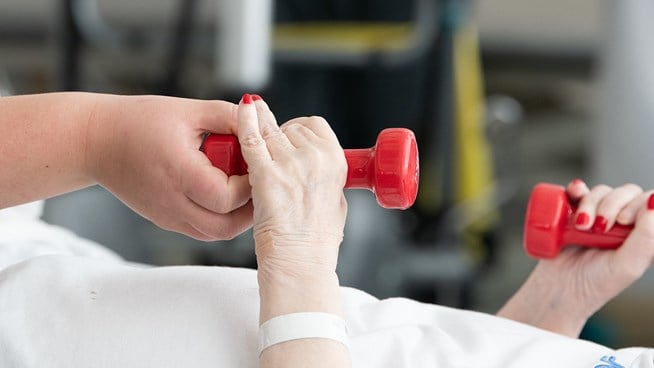 Patient som ligger ned och tränar med hantlar