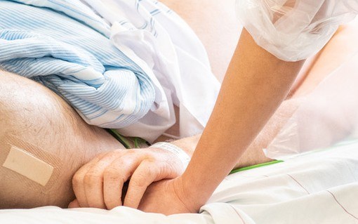 Patient med covid-19 håller en medarbetares hand.