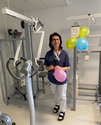 En kvinna står i ett gym och håller i ballonger.