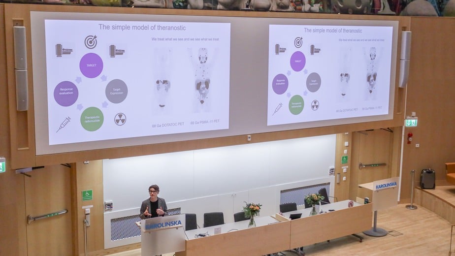 Föreläsare står nere i en stor föreläsningssal på Karolinska och föreläsaer
