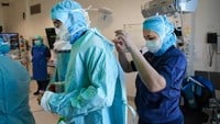 En ortoped får hjälp med att knyta sina operationskläder.