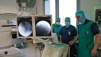 En manlig läkare och två kvinnliga sjuksköterskor tittar på röntgenbilder av patientens bäcken.