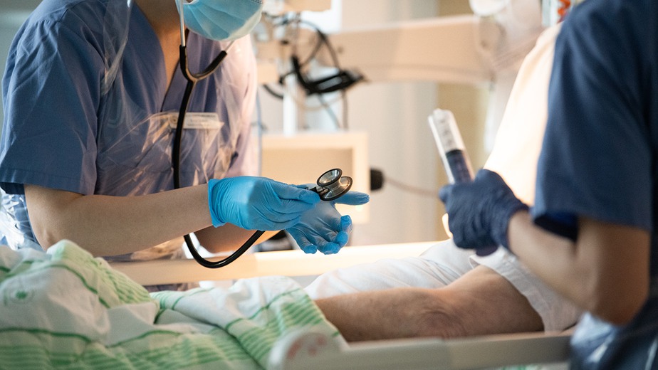 Patient i säng tas omhand av vårdpersonal