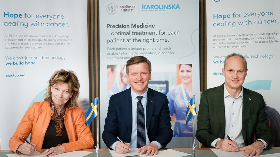 Tre personer signerar ett dokument