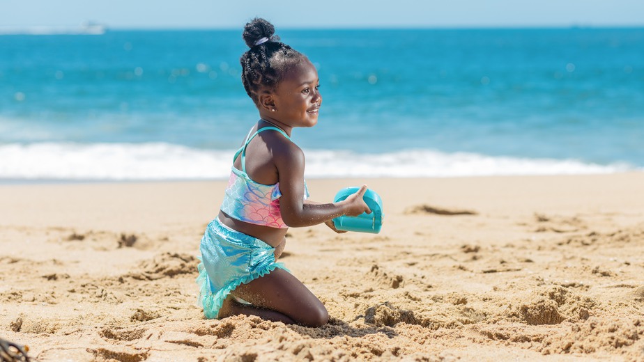 barn i badkläder leker i sanden på en strand