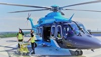 två vårdpersonal står med bår och väntar utanför helikopter