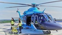 två vårdpersonal står med bår och väntar utanför helikopter