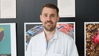 Henrik står framför en vägg med naturvetenskapliga bilder
