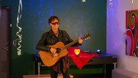 Mellostjärnan Greczula spelar akutstisk gitarr på scenen på Sommarfesten 2025