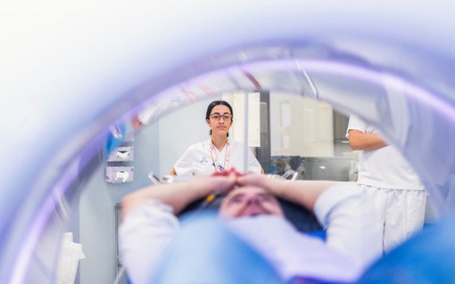 Bild på patient inuti röntgenutrustning. En röntgensjuksköterska tittar in.