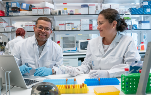 En manlig och en kvinnlig forskare sitter bredvid varandra vid en labbänk.