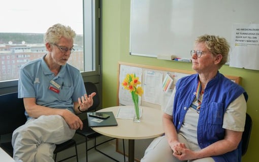 Henrik Arnell och Christina Wahlstedt sitter vid ett bord i ett personalrum på plan 11 med en påskblomma mellan sig och berättar om BANK