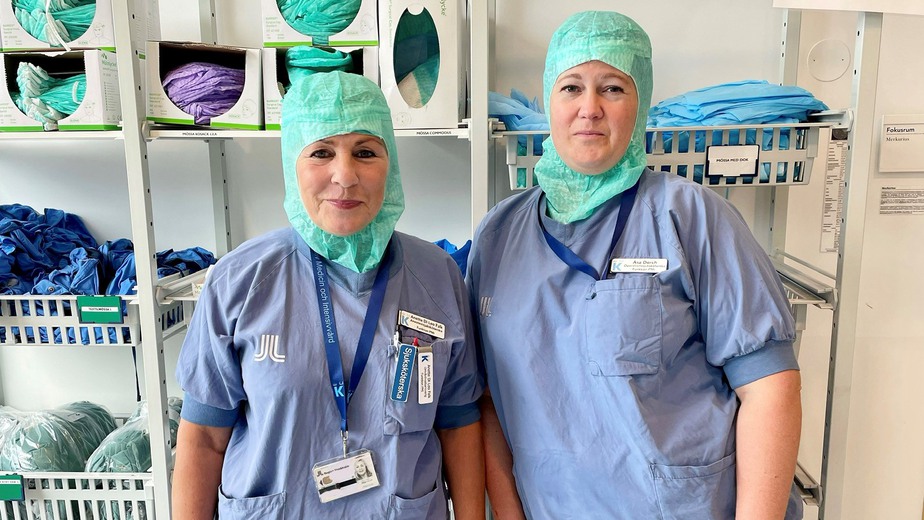 Två operationssköterskor Anette Di Leo Falk och Åsa Dorch står i operationskläder och ler och tittar in i kameran