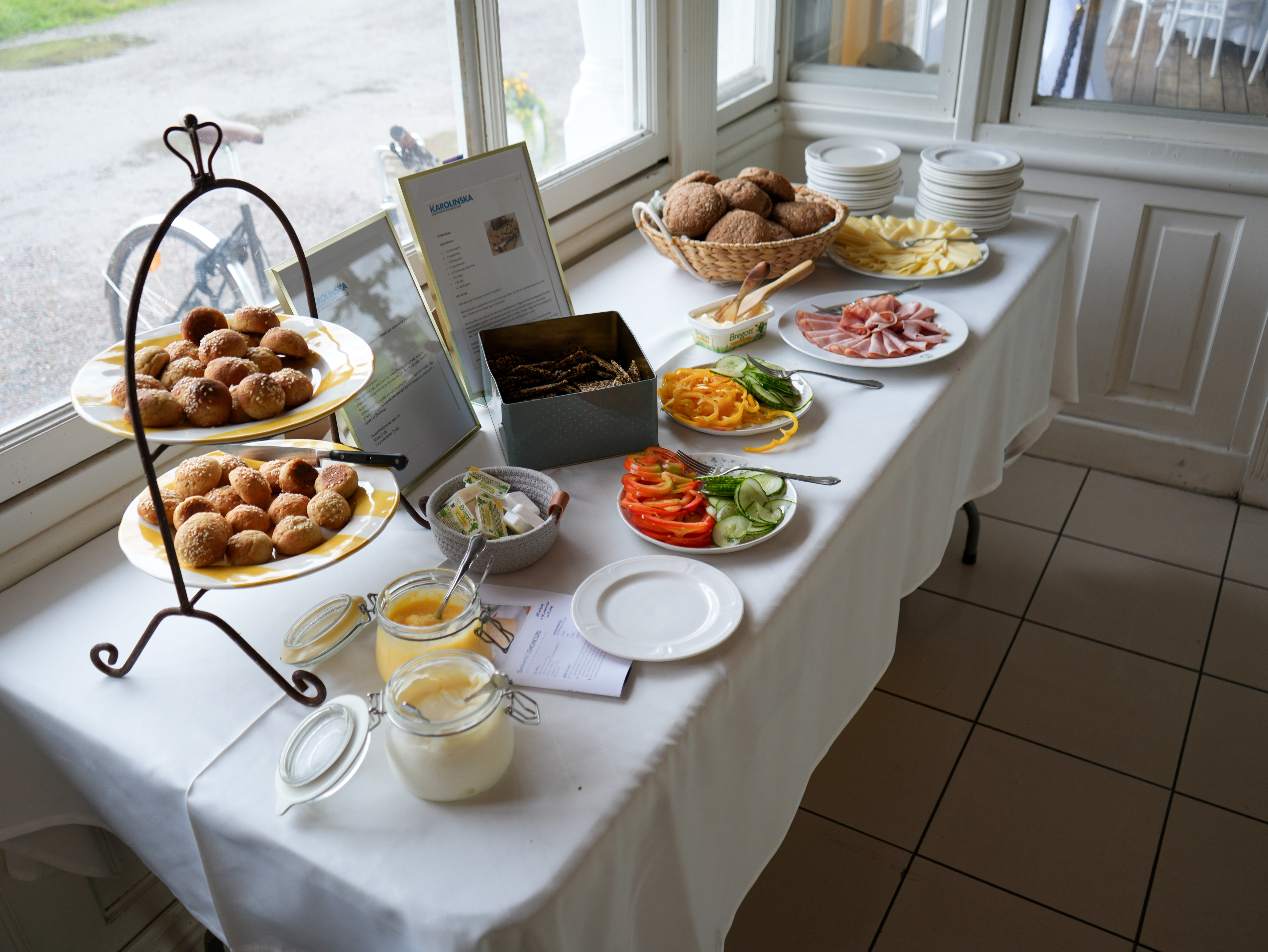 Bord med vit duk, dukat med bröd och pålägg.
