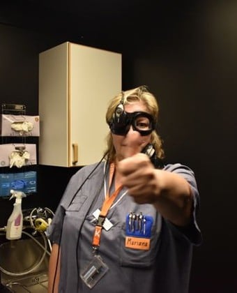 Undersköterskan Mariana Hansson håller upp och tittar på sin tumme genom ett par svarta specialglasögon.