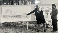 Några personer som står och pekar på en byggnadsritning.