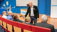 man hälsar på sittande