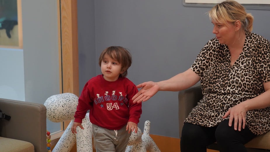 Malik leker i väntrummet och mamma Sari sitter i soffan och väntar