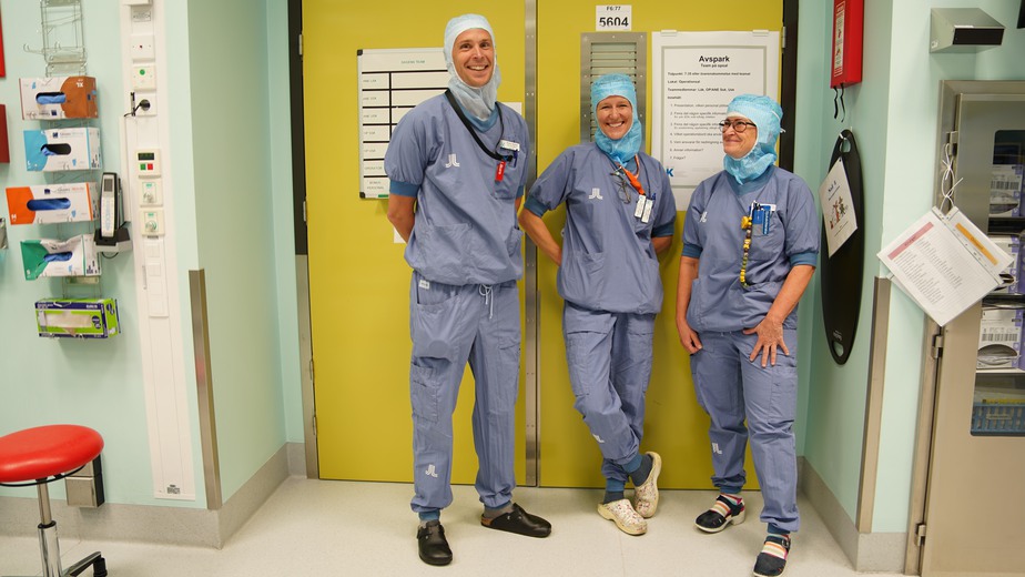 Barnoperationsteamet står framför en stor gul dörr inne i operationssalen.