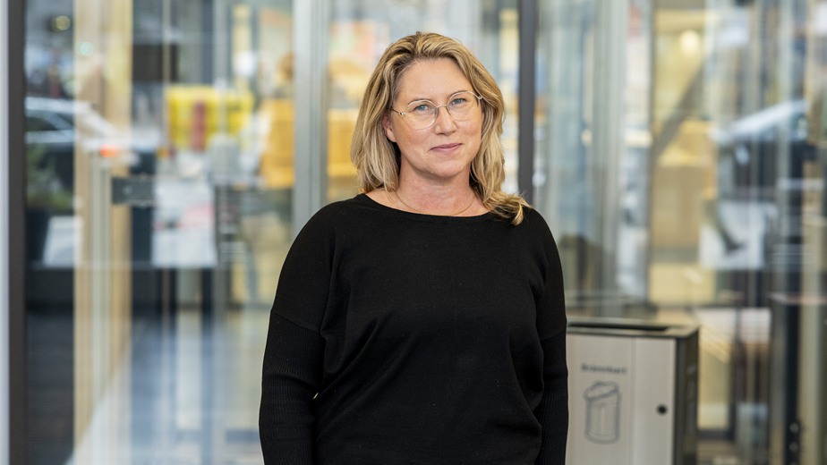 Louise Rosenlund i svarta kläder står i huvudentrén till Karolinska universitetssjukhuset i Solna.