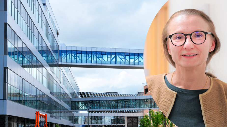 En kvinna med glasögon står framför en byggnad.