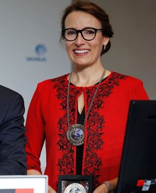 Heidi Stensmyren bär en röd dräkt och visar upp en inramad silvermedalj.