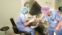 En kirurg sitter vid en operationsrobot.