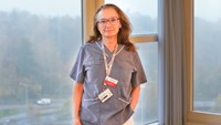 Kvinna står framför ett stort fönster.