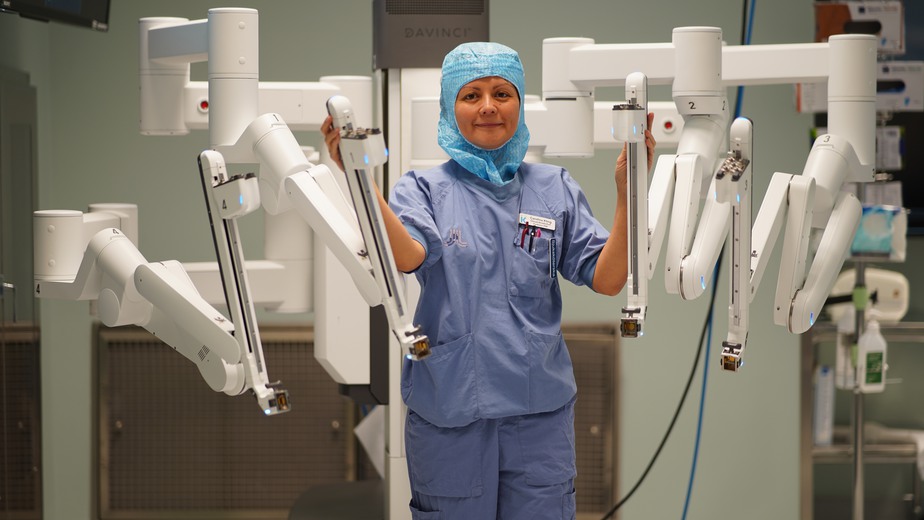 Carolina Kling, omvårdnadschef på Bukoperation, står framför en  fyraarmad da Vinci-robot