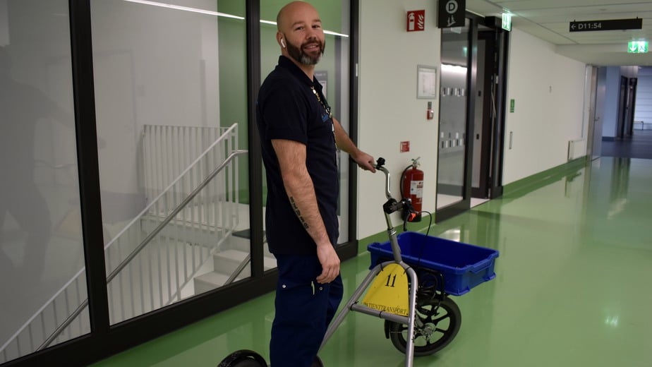 En man står vid en sparkcykel som används vid transport av bland annat läkemedel.