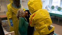 två personer i skyddsdräkter med patient